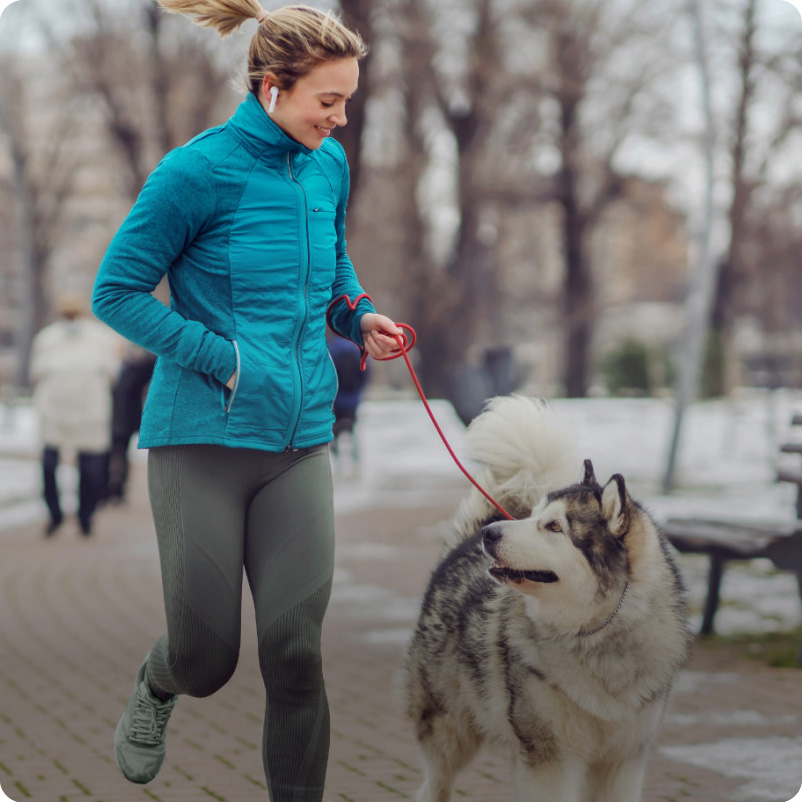 A woman in a black winter jacket with comfortemp® insulation talking on the phone and walking her bicycle.