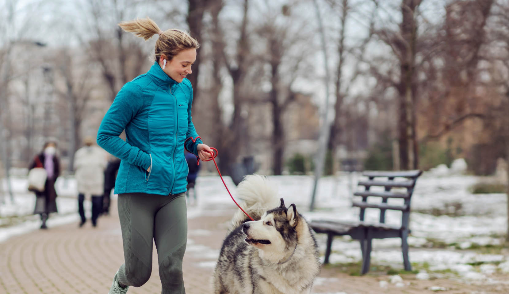 A woman in a black winter jacket with comfortemp® insulation talking on the phone and walking her bicycle.